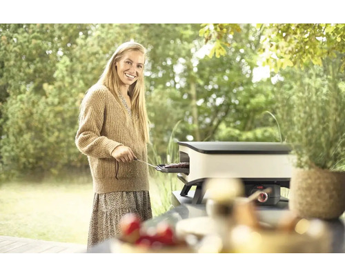 Frau grillt auf einem Tischgrill im Garten.
