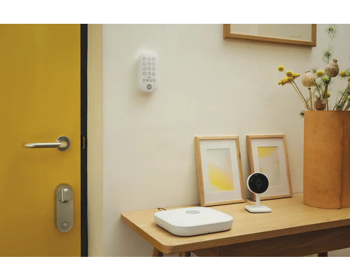 Szene mit Sicherheitssystemkomponenten von Yale, darunter eine Tastatur, eine Basisstation und eine Kamera auf einem Tisch