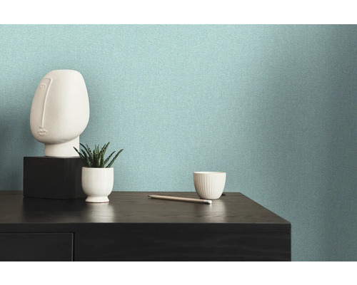 Helle, strukturierte Vliestapete an einer Wand neben einer Kommode mit Dekorationen.