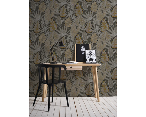 Raumansicht mit Schreibtisch, Stuhl, Lampe und gemusterter Tapete mit Blattmotiven