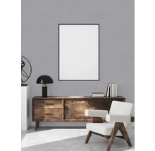 Wohnzimmer mit Holzkommode, Bilderrahmen und Sessel