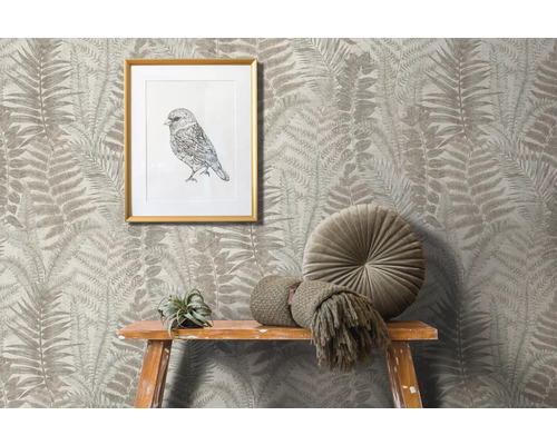 Szene mit Farnmuster-Tapete, gerahmtem Vogelbild, rundem Kissen und Dekoration auf einem Holzhocker