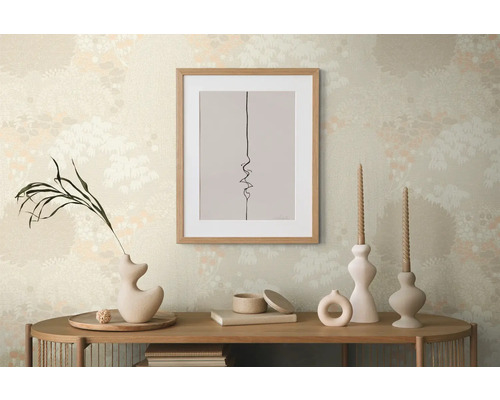 Dekorative Szene mit einem gerahmten Bild, Vasen und Kerzen auf einem Holztisch vor einer gemusterten Tapete.