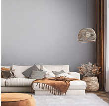 Helles Wohnzimmer mit Sofa, Kissen, Decke und Dekorationen in einem natürlichen Design