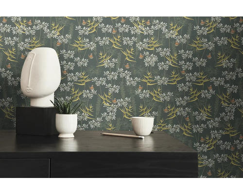 Dekoratives Zimmer mit Blumentapete, Skulptur und Zimmerpflanze auf einem Tisch