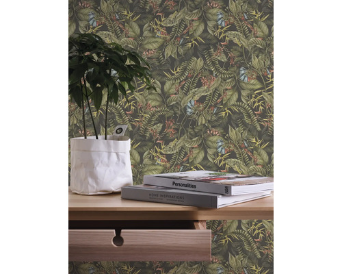 Nahaufnahme einer Wand mit einer Dschungeltapete mit Pflanzen und Blumen, ergänzt durch eine Pflanze im Topf und Bücher auf einem Holztisch.