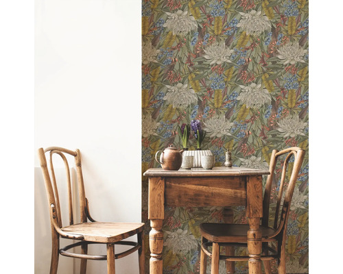 Raumansicht mit floral gemusterter Tapete, Holztisch und zwei Holzstühlen.