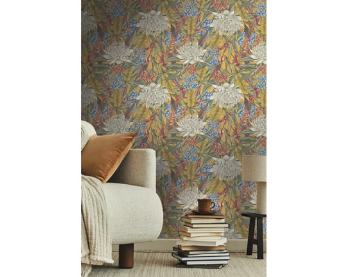 Wohnzimmer mit floraler Vliestapete, Sofa und Bücherstapel.