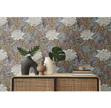 Raumansicht mit floral gemusterter Tapete, Kommode mit Rattangeflecht und Dekorationsgegenständen