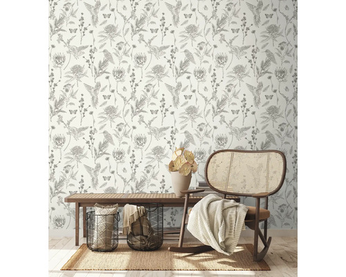 Dekorativer Raum mit einer Tapete mit Vogel-, Blumen- und Schmetterlingsmuster, einem Teppich, einer Bank, Körben und einem Schaukelstuhl.