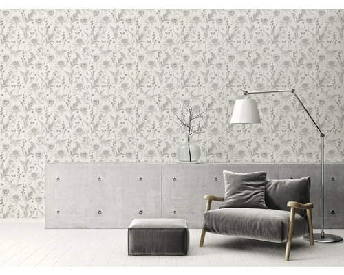 Raumansicht mit einer Tapete mit Blumenmuster, einem Sessel, einer Stehlampe und einem Couchtisch.