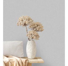 Dekorative Vase mit Trockenblumen auf einem Tisch mit Kissen vor einer strukturierten Wand
