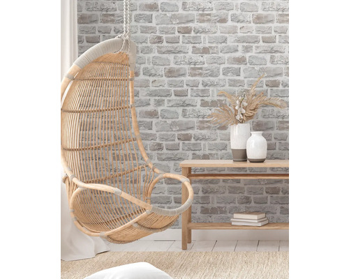 Hängesessel aus Rattan in einem hellen, freundlichen Raum mit Ziegelwandtapete