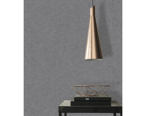 Nahaufnahme einer grauen Tapete mit feiner Struktur in einem Raum mit einer Lampe und dekorativen Gegenständen.