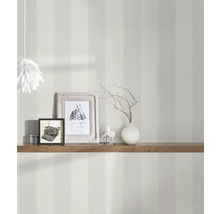 Innenaufnahme eines Raumes mit gestreifter Tapete, dekoriert mit einer Holzablage, Fotorahmen und einer Lampe