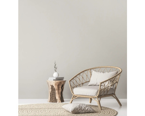 Helle Inneneinrichtung mit Rattansessel, rundem Teppich und Beistelltisch aus Holz.