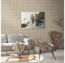 Wohnzimmer mit Sofa, Sessel und einem Wandbild mit Strandmotiv
