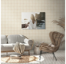 Wohnzimmer mit Sofa, Rattansessel und Wandbild mit Strandmotiv