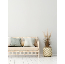 Dekoratives Sofa mit Kissen und einer Pflanze in einem Korb auf einem weißen Holzboden.