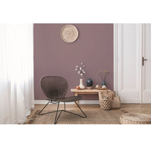 Wohnzimmer mit Rattansessel, Holztisch und Dekorationen auf einem Teppich