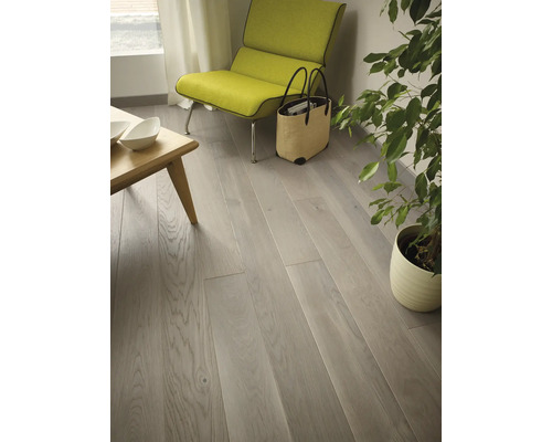 Helles Wohnzimmer mit Holzboden, Sessel und Zimmerpflanze