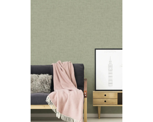 Wohnszene mit einer strukturierten Tapete, einem Sofa mit Decke und Kissen, sowie einem kleinen Schrank mit einem London-Bild