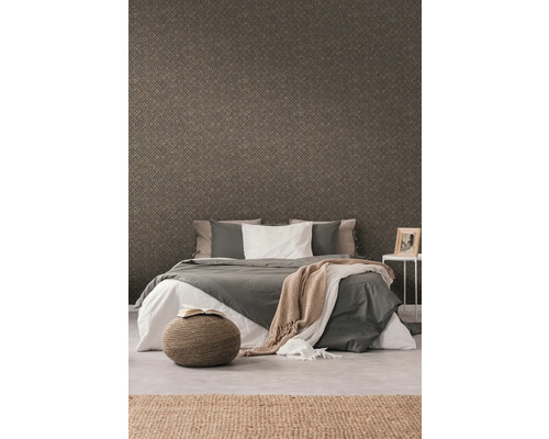 Schlafzimmer mit gemusterter Tapete, Bett, Hocker und Teppich für ein gemütliches Ambiente.