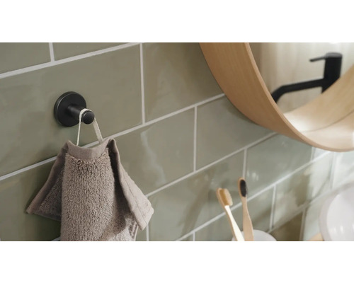 Detailansicht eines Badezimmers mit Handtuchhaken, Handtuch, Spiegel und Zahnbürsten