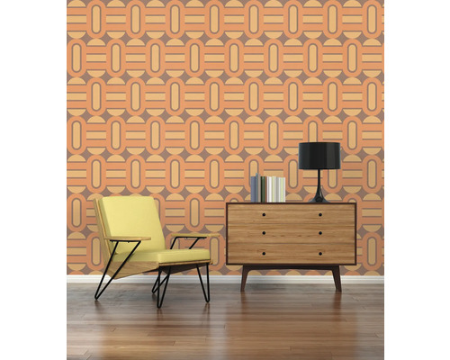 Wohnraum mit Sessel, Kommode, Lampe und Tapete mit geometrischem Muster