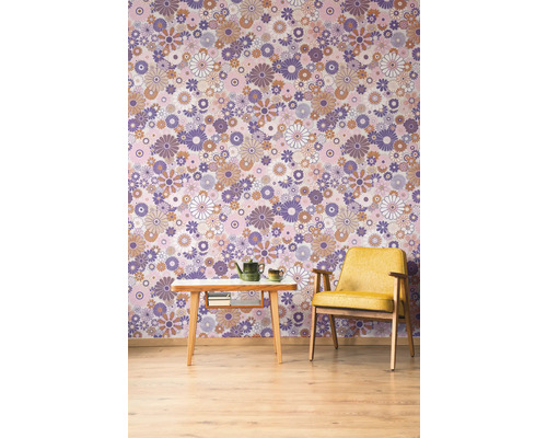 Ein Zimmer mit einer gemusterten Tapete, einem Sessel und einem Tisch mit Teekanne.