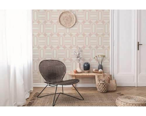 Heller Raum mit geometrischer Tapete, Korbstuhl, Holztisch und Juteteppich für ein freundliches Ambiente.