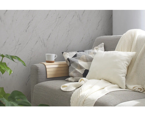 Wohnzimmer mit grauer Couch, Kissen, Decke und Wandtapete in Marmoroptik