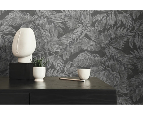 Dekoratives Stillleben mit Blättertapete, Skulptur und Pflanze auf einem Tisch.