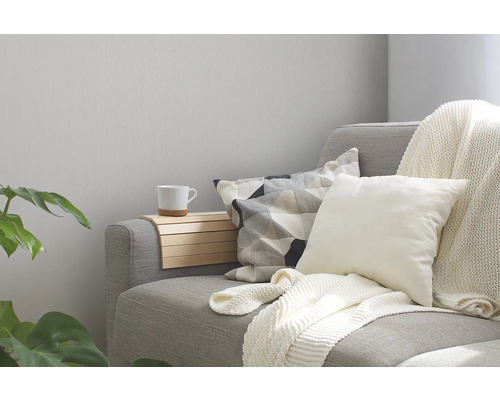 Graues Sofa mit Kissen, Überwurf und Armlehnenablage im Wohnzimmer.