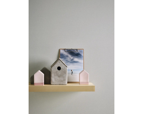 Dekorative Häuser aus Beton und Holz auf einem Regal mit einem Bild im Hintergrund.