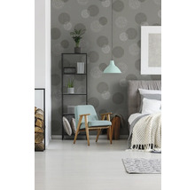 Schlafzimmer mit Bett, Sessel, Regal und Tapete mit Kreismuster