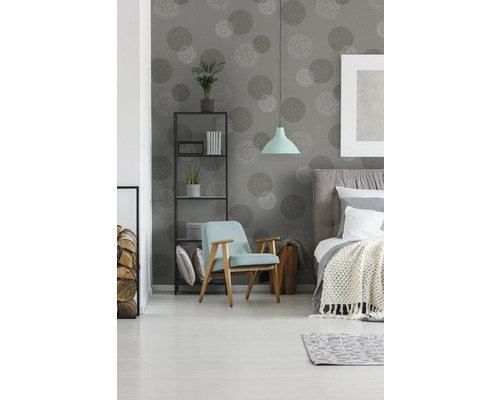 Schlafzimmer mit Bett, Sessel, Regal und Tapete mit Kreismuster