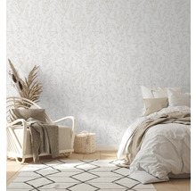 Helles Schlafzimmer mit floral gemusterter Tapete, Sessel und Bett.