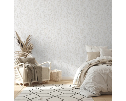 Helles Schlafzimmer mit floral gemusterter Tapete, Sessel und Bett.