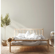 Helles Schlafzimmer mit Holzbett, Pflanze und Dekoration