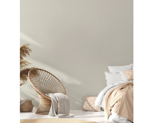Helles Schlafzimmer mit Rattansessel, Bett und Dekorationen im Boho-Stil.