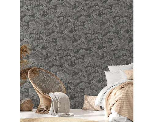 Dekoratives Zimmer mit Blattmuster-Tapete, Sessel und Bett.