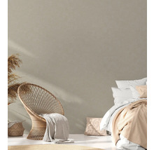 Helles Schlafzimmer mit Rattan-Stuhl, Bett und dekorativen Textilien für eine gemütliche Atmosphäre.
