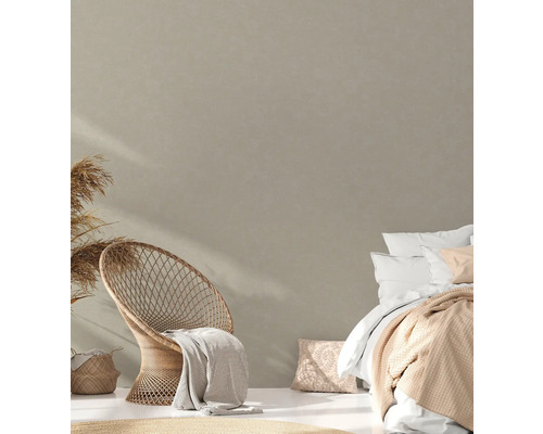 Helles Schlafzimmer mit Rattan-Stuhl, Bett und dekorativen Textilien für eine gemütliche Atmosphäre.