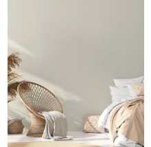 Hell gestalteter Schlafbereich mit Rattan-Stuhl und Doppelbett.
