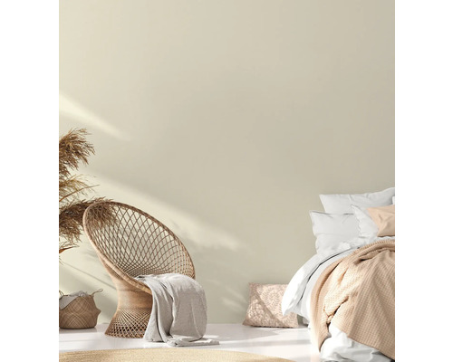 Helles Schlafzimmer mit Rattansessel, Bett und dekorativen Textilien für ein gemütliches Ambiente