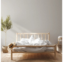 Schlafzimmer mit Holzbett, Pflanze und Accessoires für eine helle und freundliche Atmosphäre.