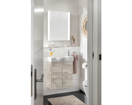 Helles Badezimmer mit Waschtisch, beleuchtetem Spiegelschrank und Toilette