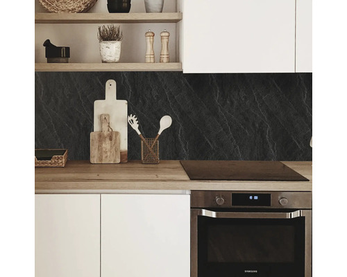 Küchenszene mit Küchenrückwand in Steinoptik, Arbeitsplatte und Küchenutensilien.