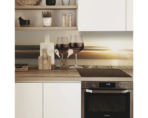 Küchenszene mit zwei Weingläsern, Schneidebrettern und einem Kochfeld vor einer Küchendekorfolie mit Meeresmotiv